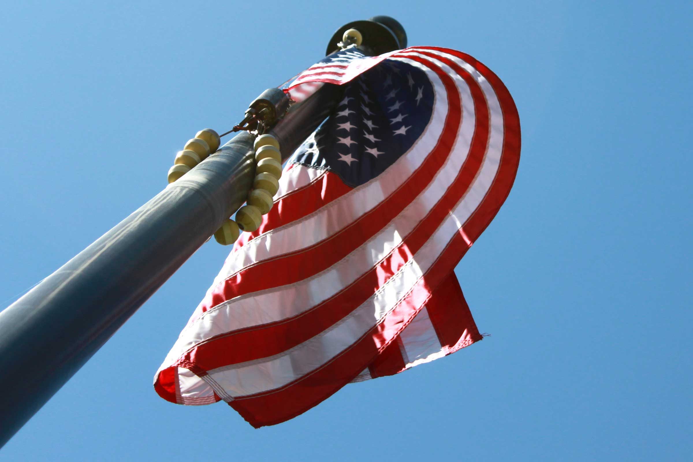 an upward view of an american flag draped in a gentle curl around its flagpole outside the historic courthouse in Hamilton County, Indiana