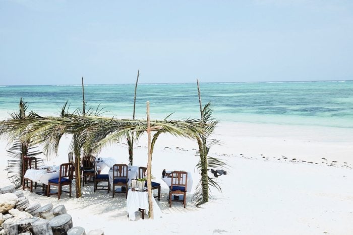 tiki hut with table and chairs on a beach by the ocean at Palms, Zanzibar