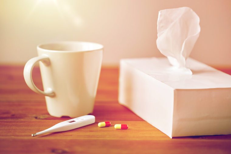 healthcare, medicine, flu and treatment concept - cup of tea, paper wipes and thermometer with pills