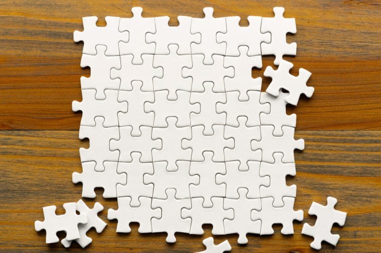 나무 배경에 흰색 퍼즐 조각입니다.  부분적으로 완성된 사각형 모양의 퍼즐 조각입니다.