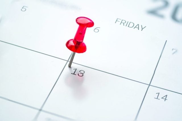 Red push pin on calendar friday the 13th day of the month