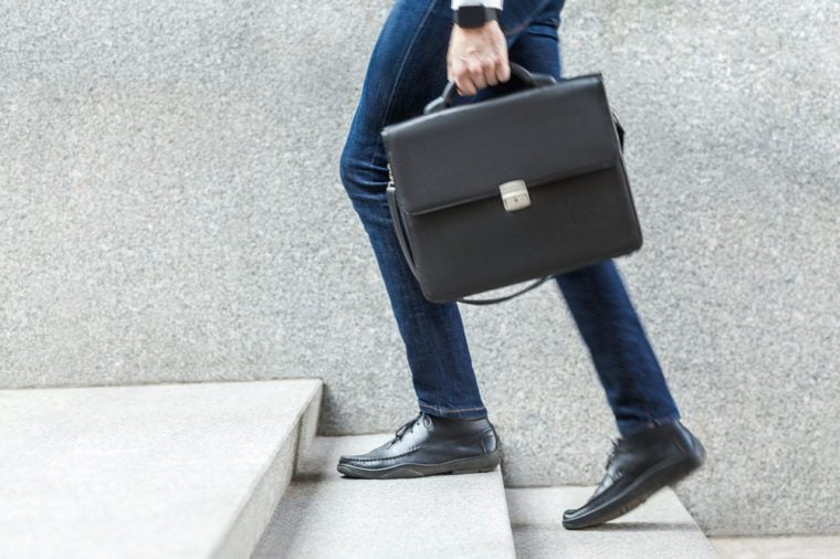 Businessman with briefcase in hand walking up on stairs. Outdoor shoot