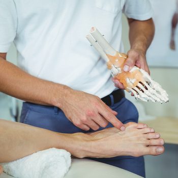 Physiotherapist explaining feet model to patient in clinic