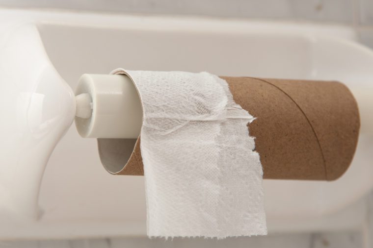 Empty roll of toilet paper mounted on a tiled wall