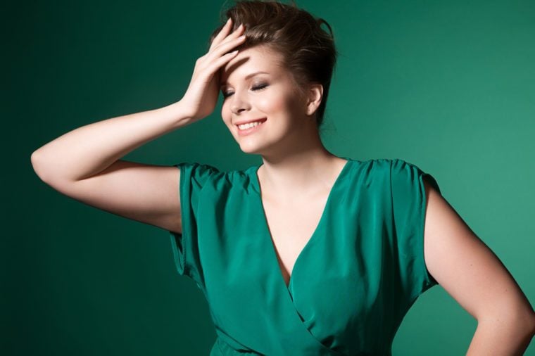 Beautiful laughing plump girl in a green evening dress and hairstyle