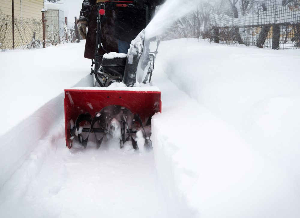 Man clears snow with snow blower after snowfall