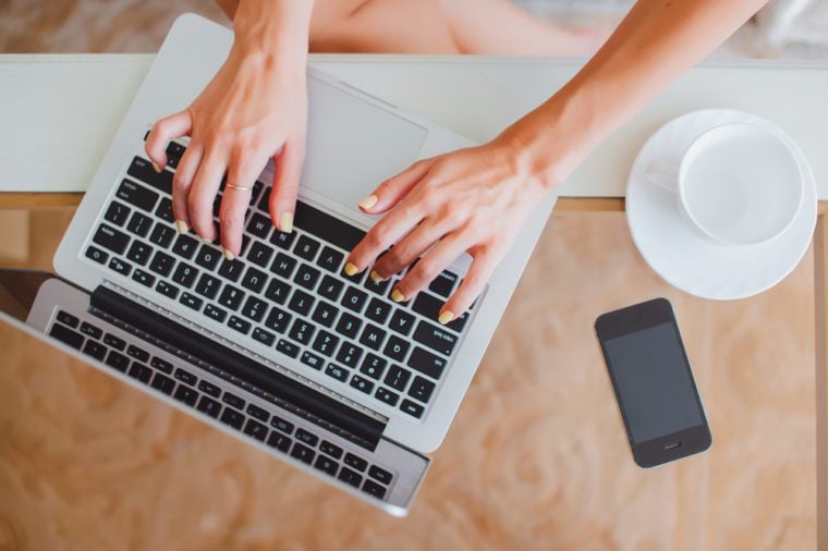 young girl woman working on a laptop sitting at home write messages to drinking coffee smiling typing on a keyboard, macbook serfing, applet style, iphone,