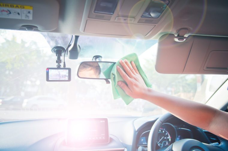 Hand cleaning the car interior with green microfiber cloth