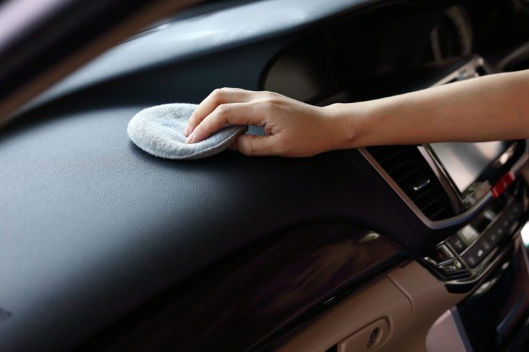 woman hand cleaning leather black console in car with soft fabric sponge waxing polished