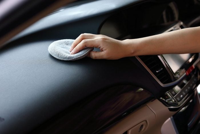 woman hand cleaning leather black console in car with soft fabric sponge waxing polished