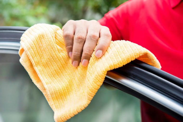 Male auto care service staff cleaning car window with microfiber cloth