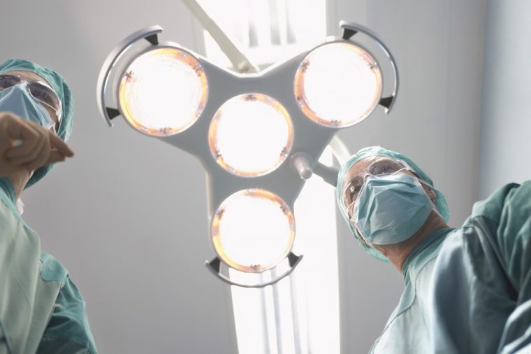 Low angle view of two surgeons under surgery lights in operating theatre