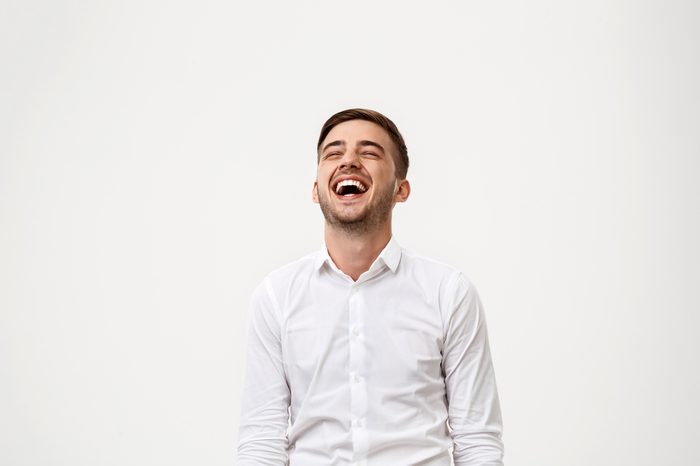 Young successful businessman smiling, laughing over white background.