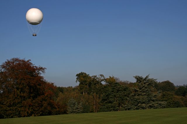 white weather balloon in the air above the trees