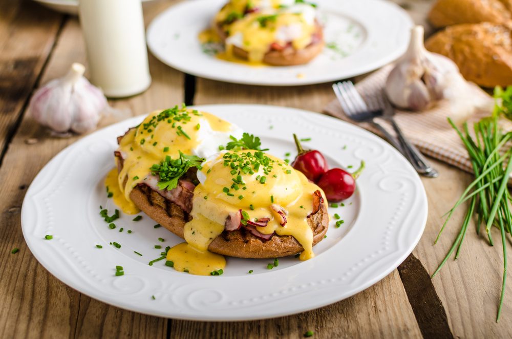 Eggs Benedict with little salad, milk and fresh herbs