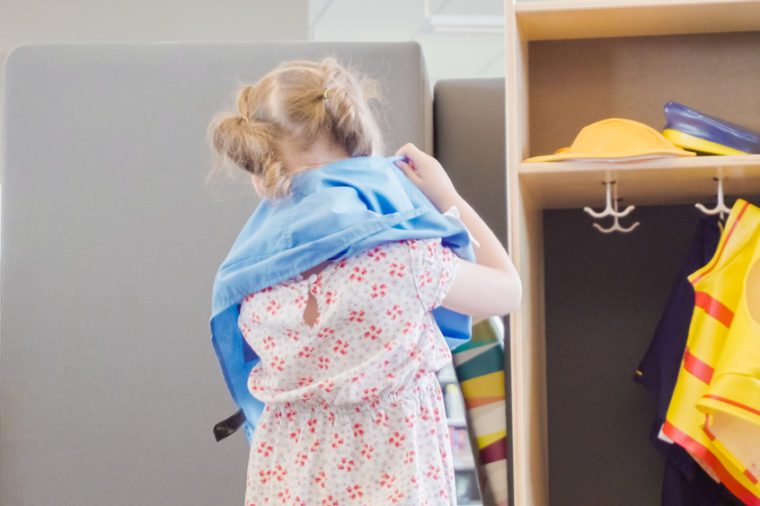 Little girl playing dress up game in kids section of public library.