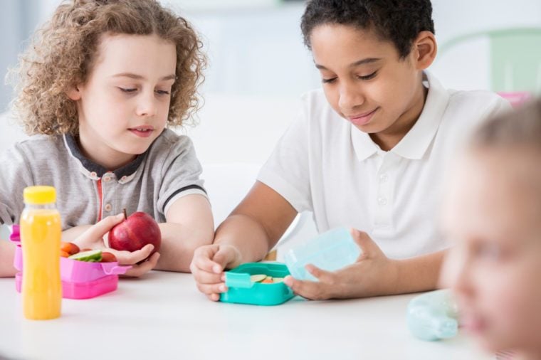 African-american boy and his friend eating an apple during break at school