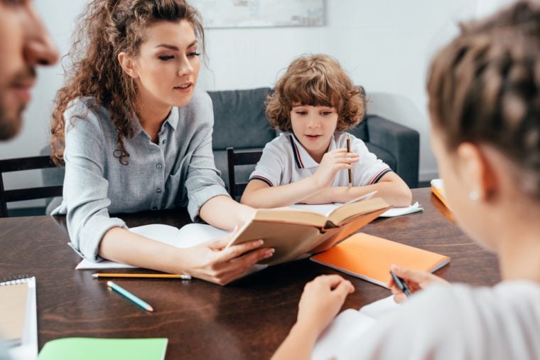 pensive young parents doing homework with kids