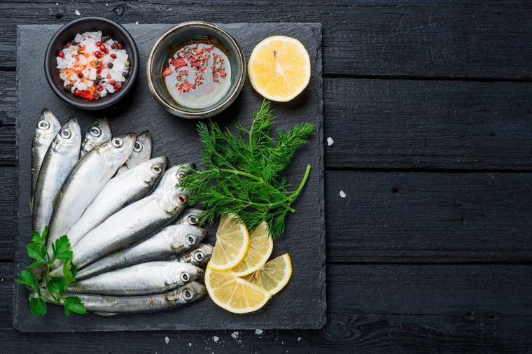 Fresh raw sardines on a dark background, top view.