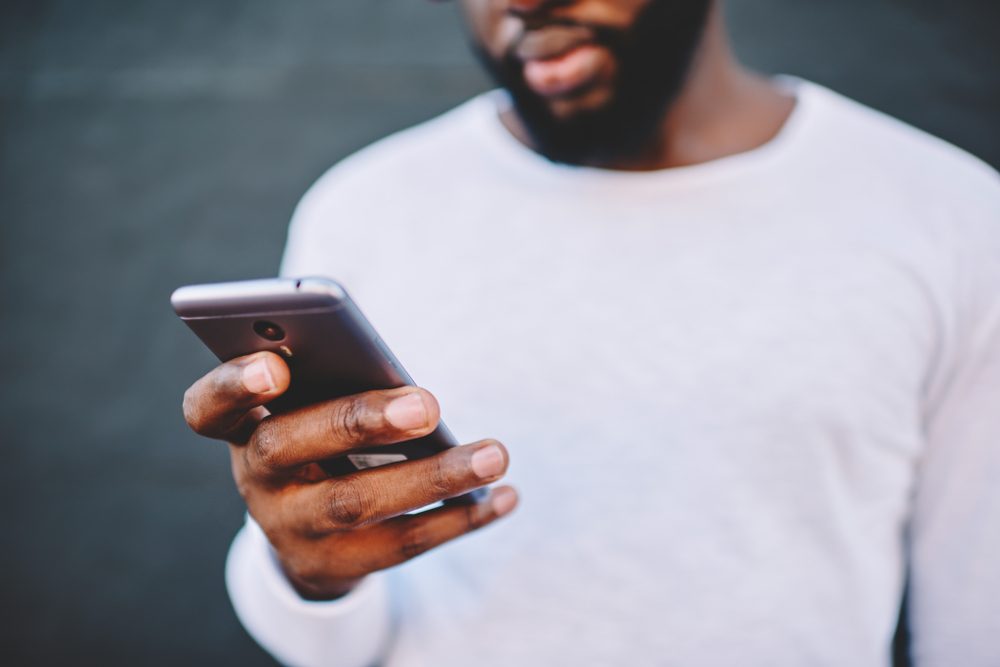 현대 스마트 폰 전화 번호를 들고 아프리카 계 미국인 남자의 자른 이미지, 야외에서
4G 인터넷 연결을 통해 소셜 네트워크에서 채팅을 위해 휴대 전화를 사용하여 흰 셔츠에 어두운 피부 남성