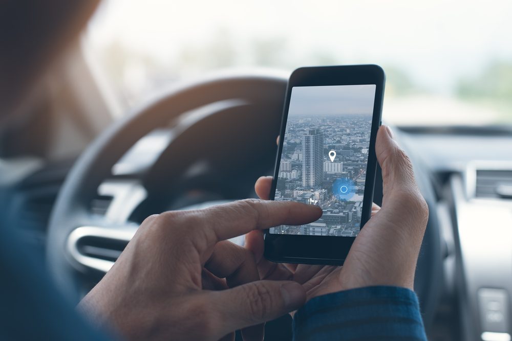 자동차를 운전하는 동안 자동차 내부의 모바일 스마트 폰을 통해 GPS 또는 네비게이터 응용 프로그램에서 목적지 방향 또는 주소를 검색하는 사람, 클로즈업