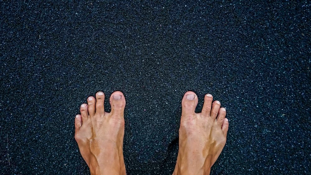 feet on black sand beach