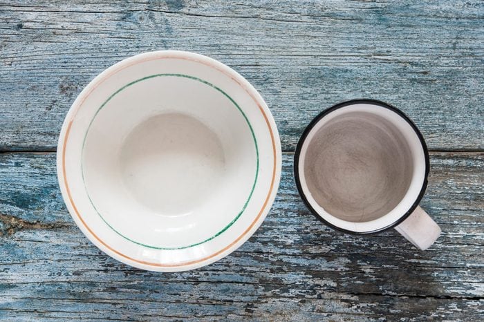 Empty plates and bowls on blue wooden background. Top view with copy space 