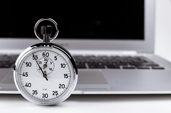 Silver stopwatch with silver laptop in the background