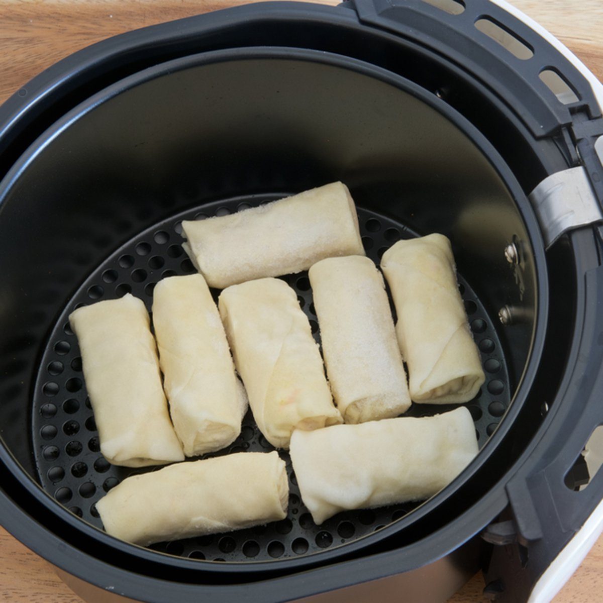 Electric fryer with basket of frozen spring rolls