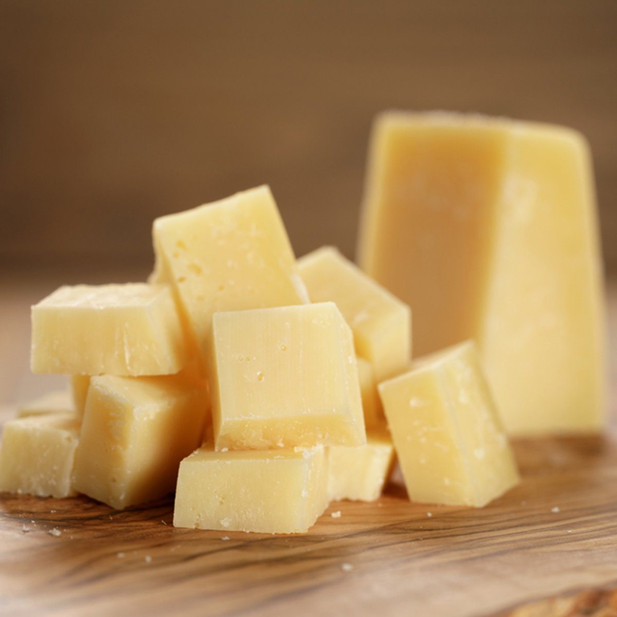 parmesan cubes on olive wooden board, shallow focus