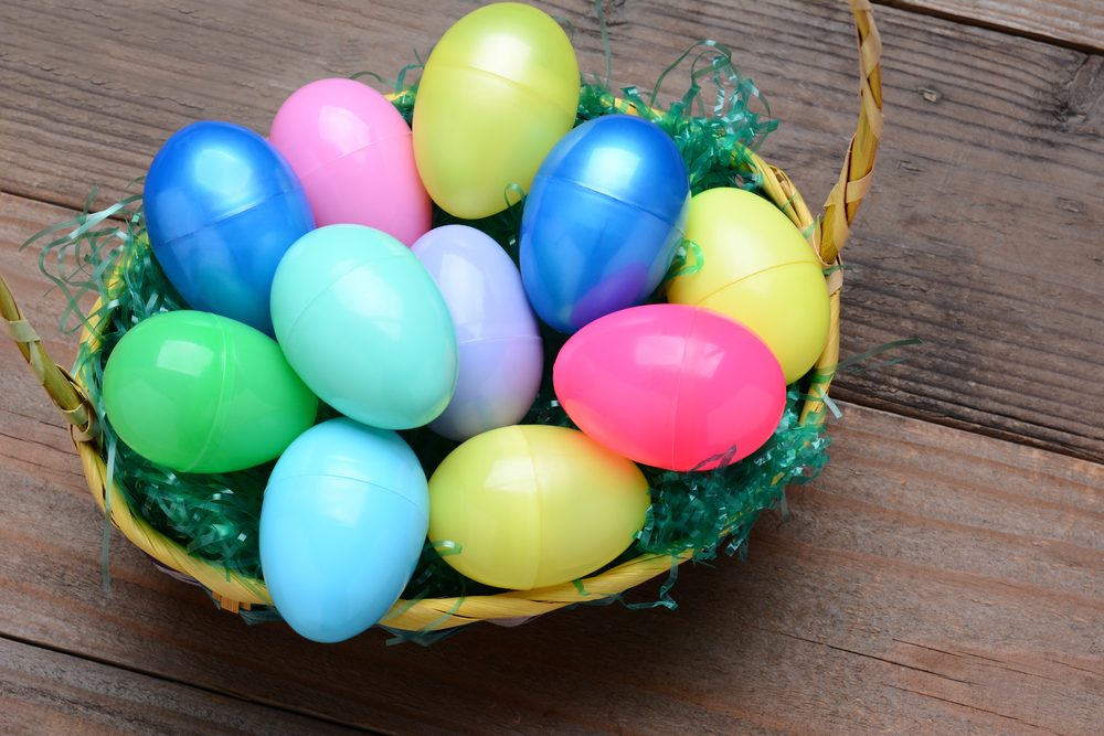 High Angle view of a basket filled with colorful plastic Easter eggs. Horizontal format on a rustic wood background.