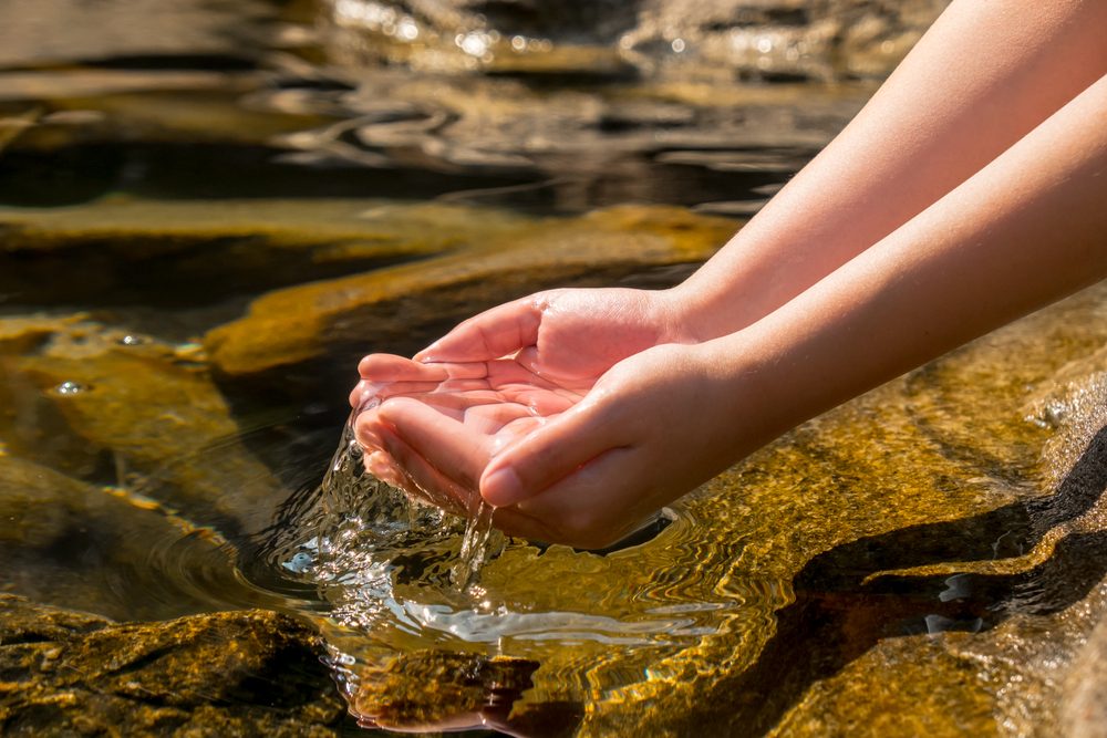 hand holding transparent clear water from natural well