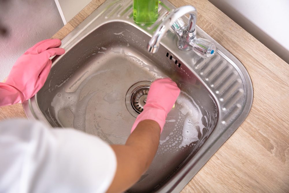 An Overhead View Of A Person's Hands In Pink Gloves Washing The Kitchen Sink