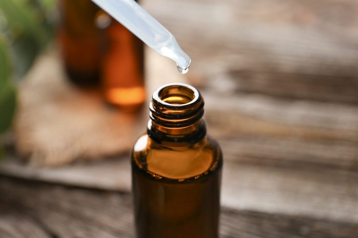 Eucalyptus essential oil dripping from pipette into bottle, closeup