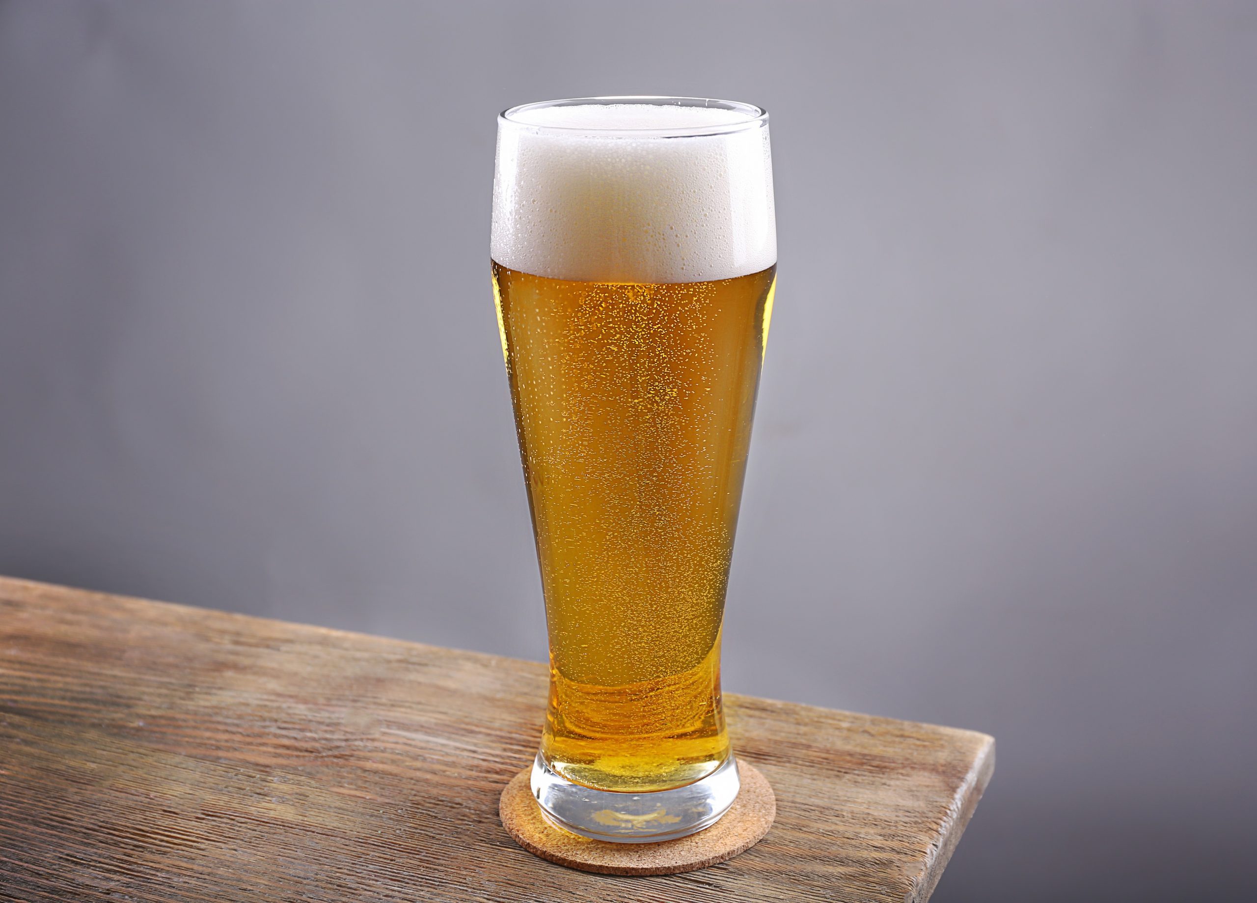 Glass of light beer on grey background