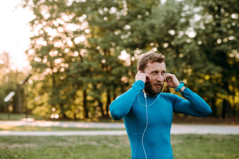 Music is always with me. Portrait of athletic mature man before run.