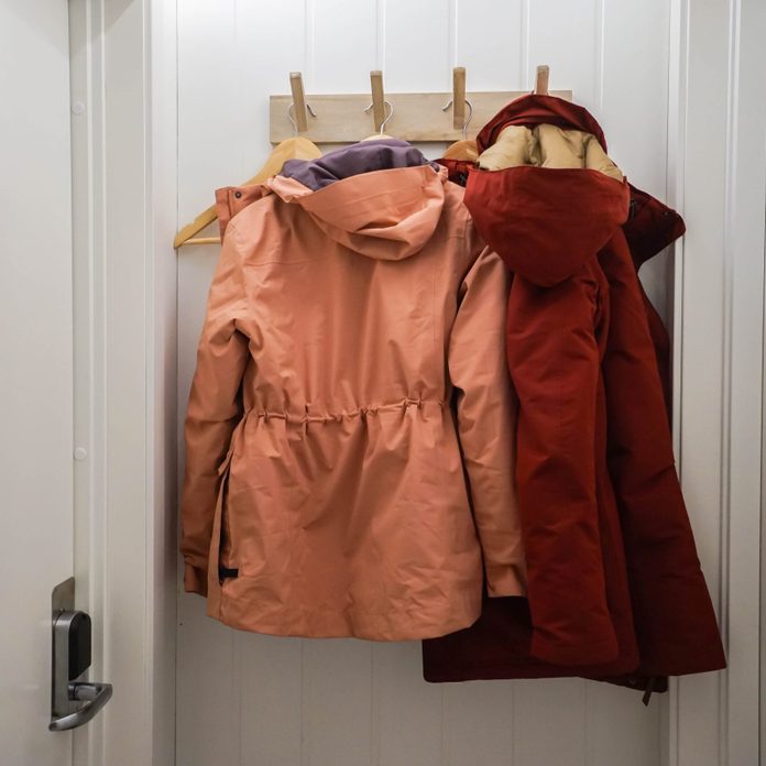 men and women winter jacket hang at wall hook at house door