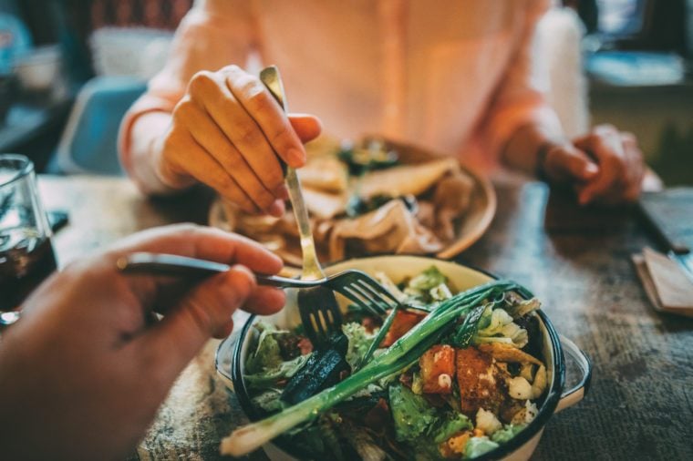 woman taking food off someone else's plate in a restaurant