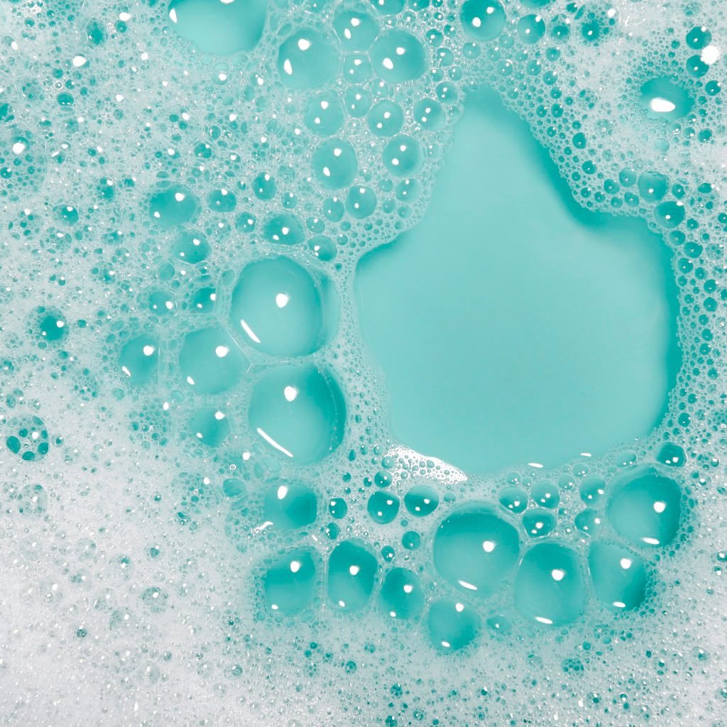 Close-up of soap bubbles with water on a blue background.