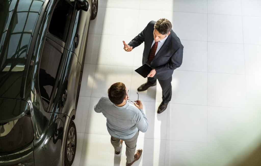 Above view of car salesperson talking to his customer in a showroom.