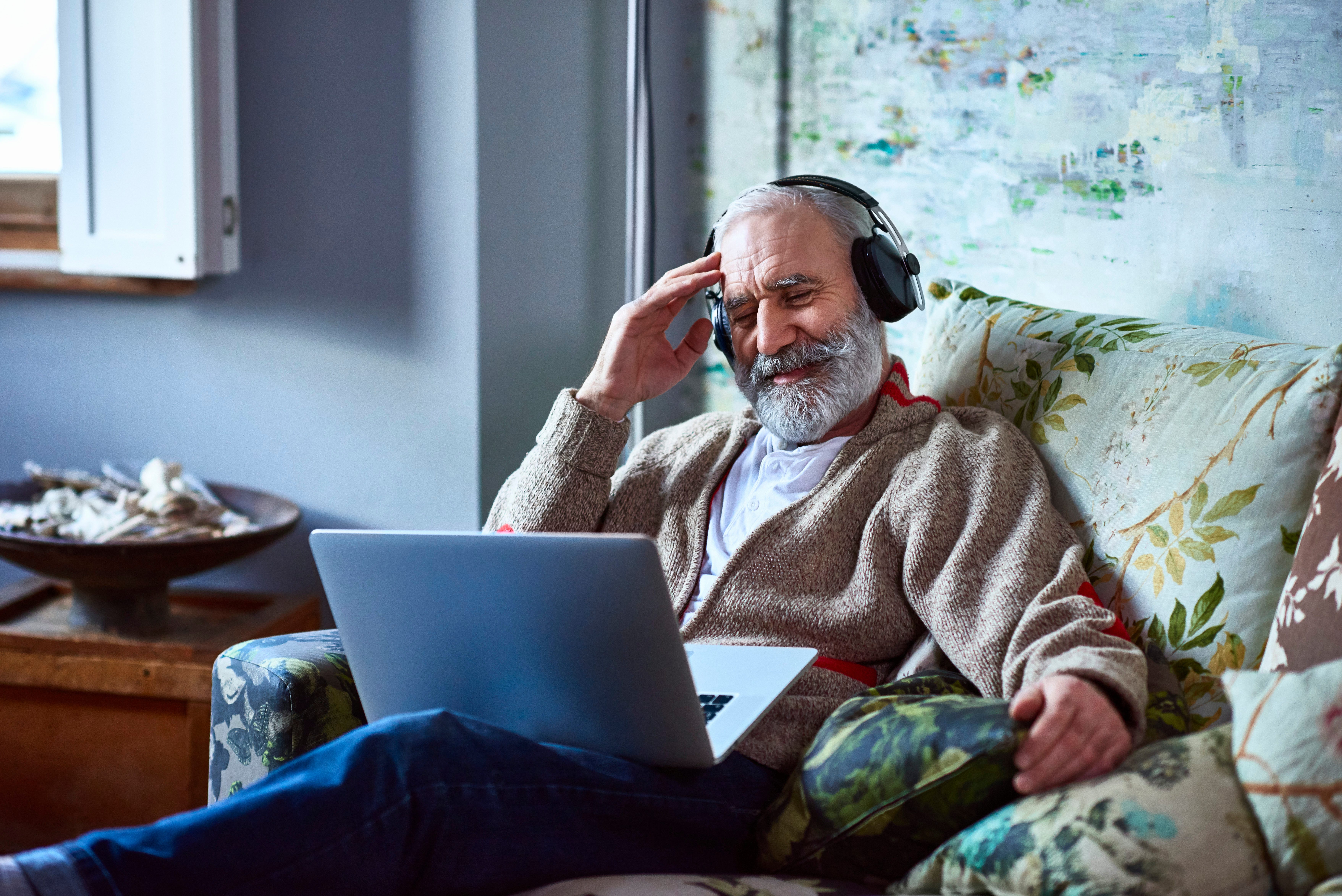 Portrait of mature man streaming movie on laptop wearing headphones