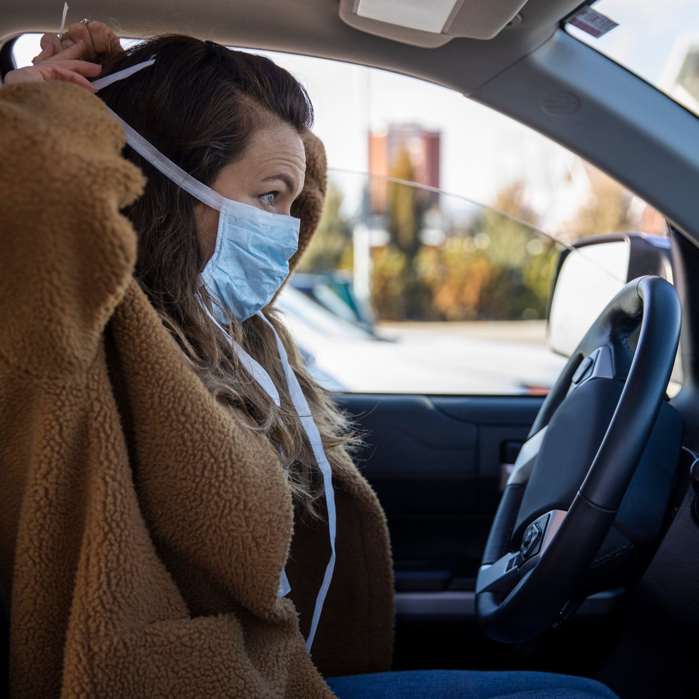 A woman driving her vehicle wearing latex gloves and a mask during the COVID-19 pandemic.