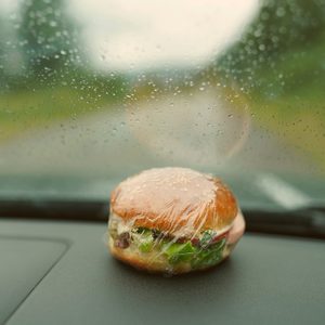 wrapped burger lies on the car dashboard