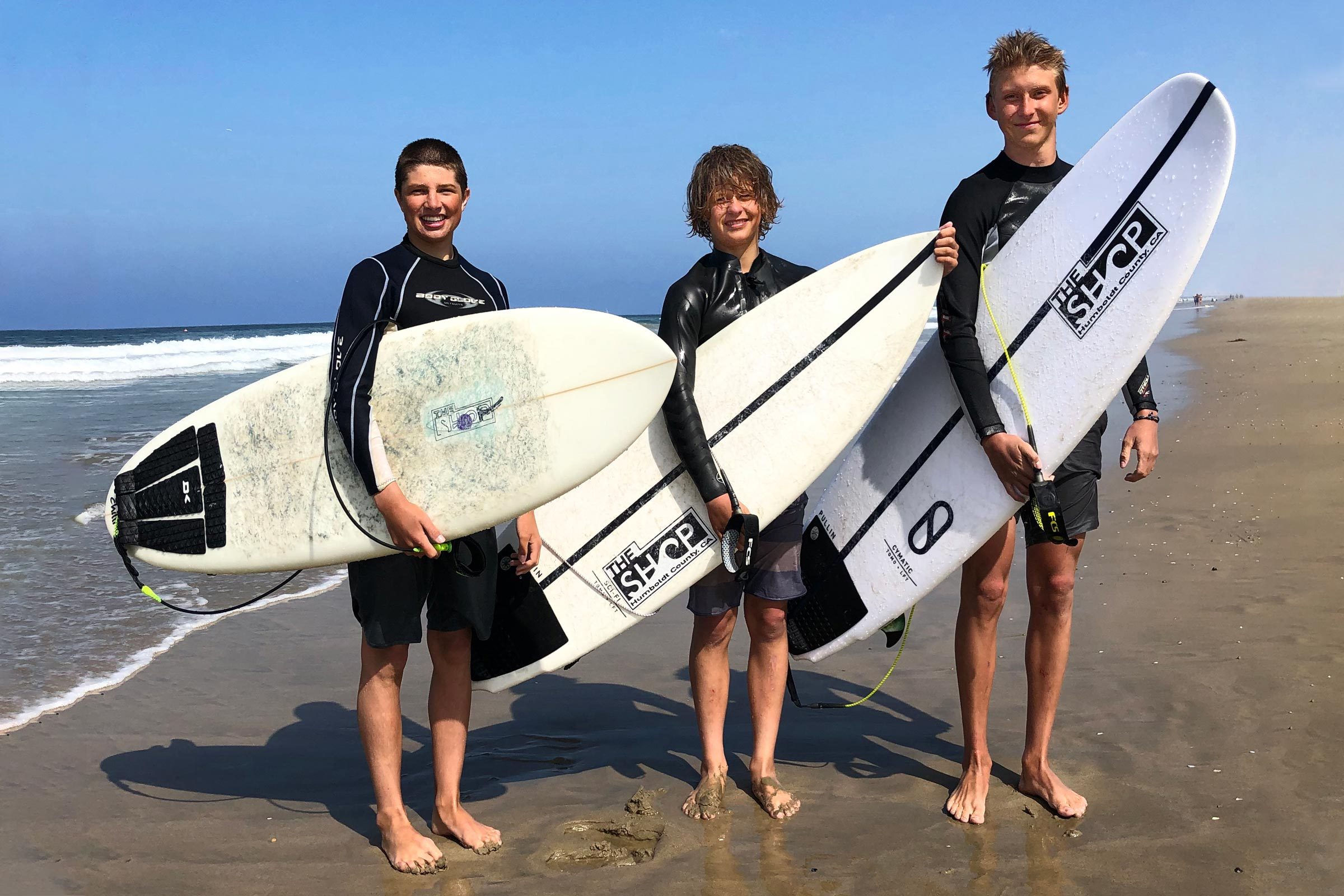 Spenvser Stratton, Taj Ortiz-Beck, and Adrian York on the beach holding surf boards