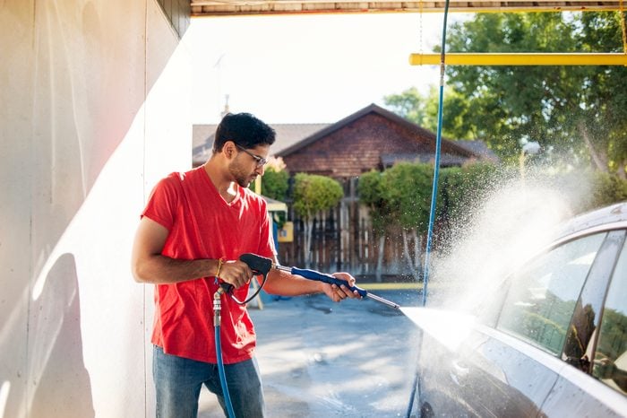 Man washing car in garage on sunny day