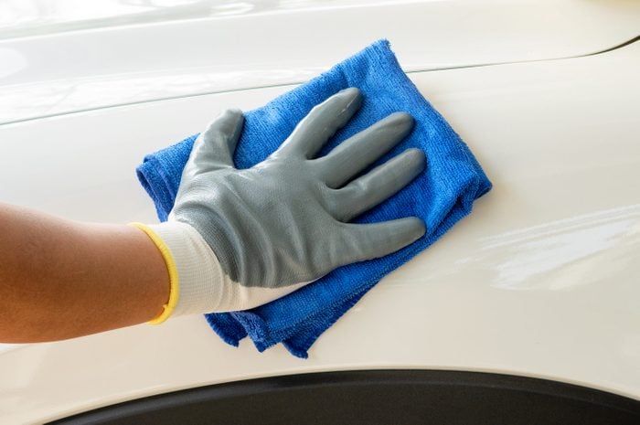 Car detailing - the man holds the microfiber in hand and polishes the car. Selective focus.