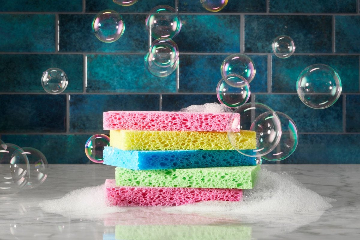 pile of colorful sponges on a kitchen counter with suds and bubbles