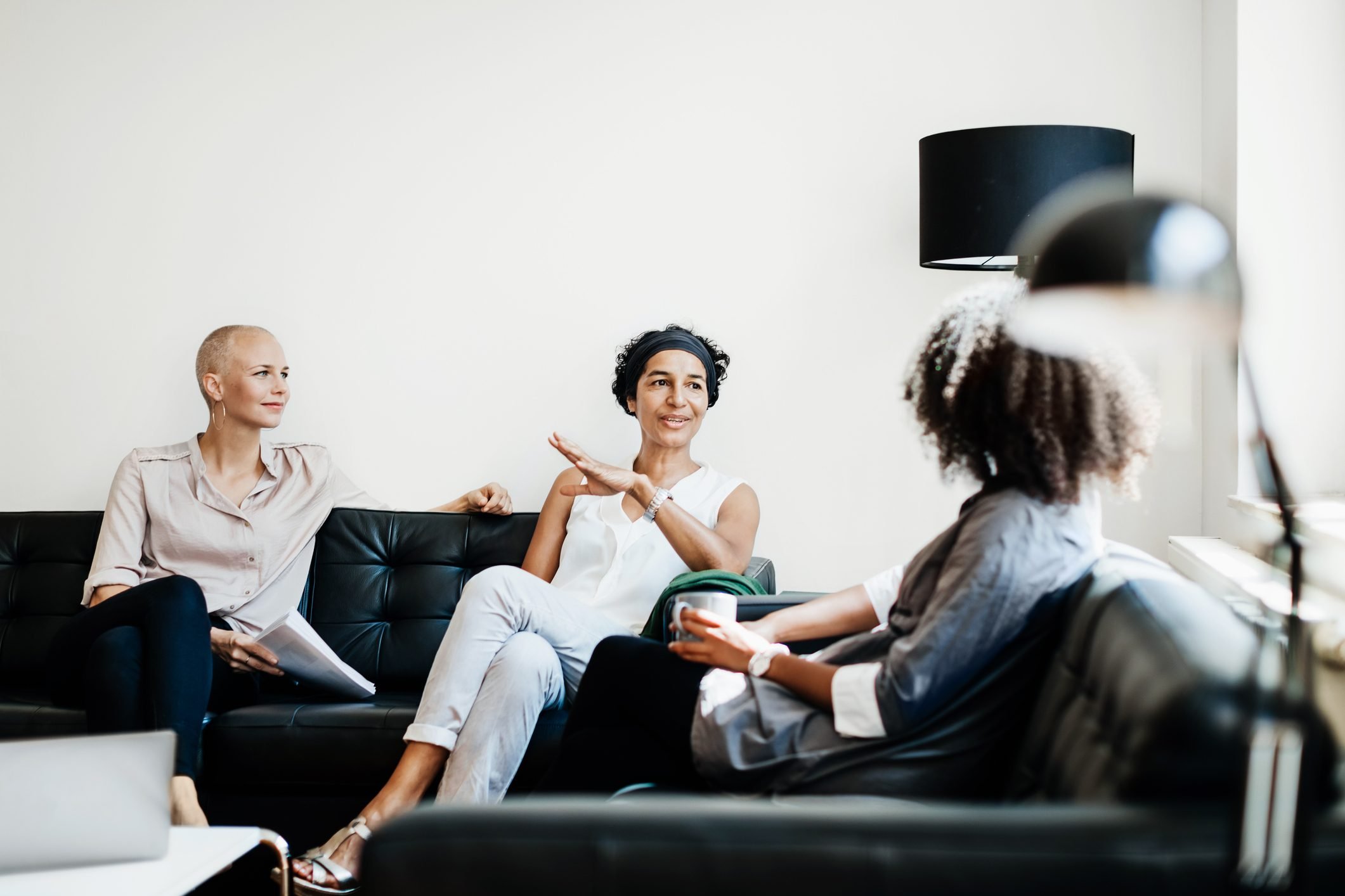 Colleagues Sitting On Couch Talking At Office.