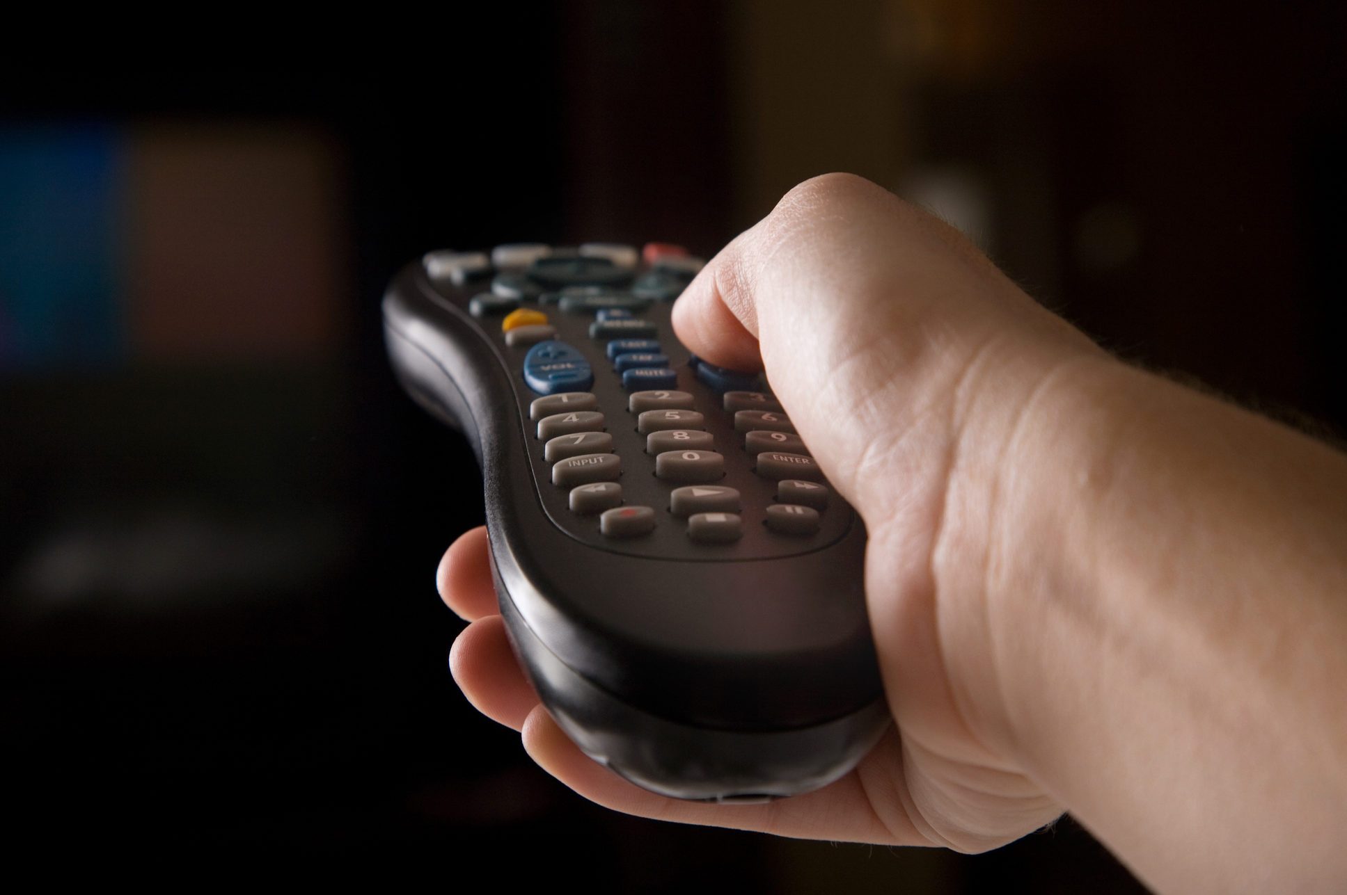 A hand holding a remote to change channels