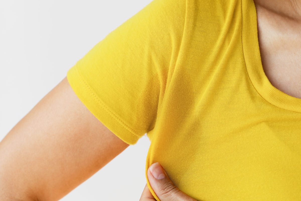 close up of a sweat stain on an anonymous woman wearing a yellow shirt